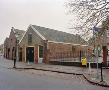 840120 Gezicht op de voor- en zijgevel van het voormalige pakhuis Wijde Doelen 10 te Utrecht. Rechts het schoolplein ...